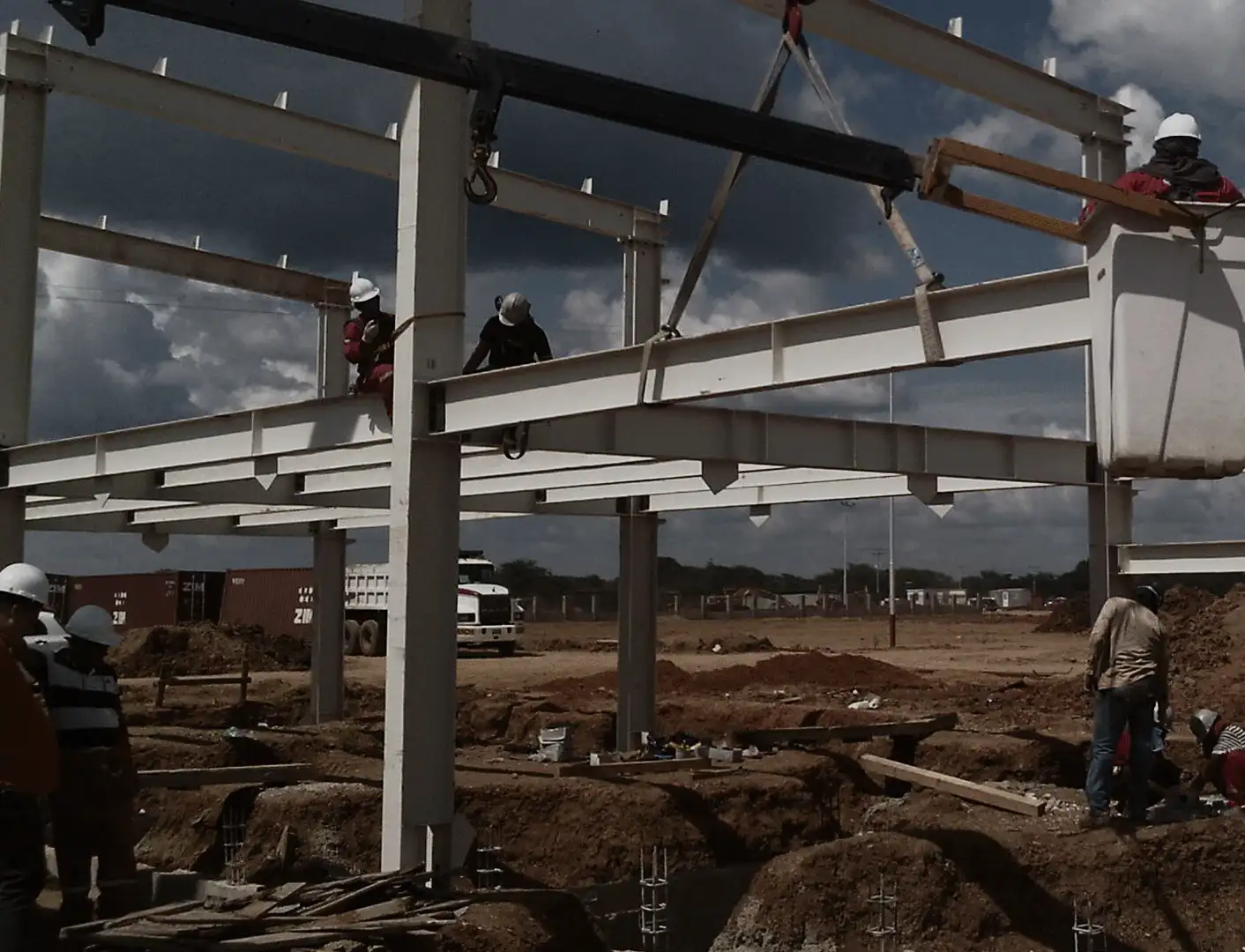 ONIX crew erecting beams at height over the columns of an industrial hall, with a crane and a boom lift
