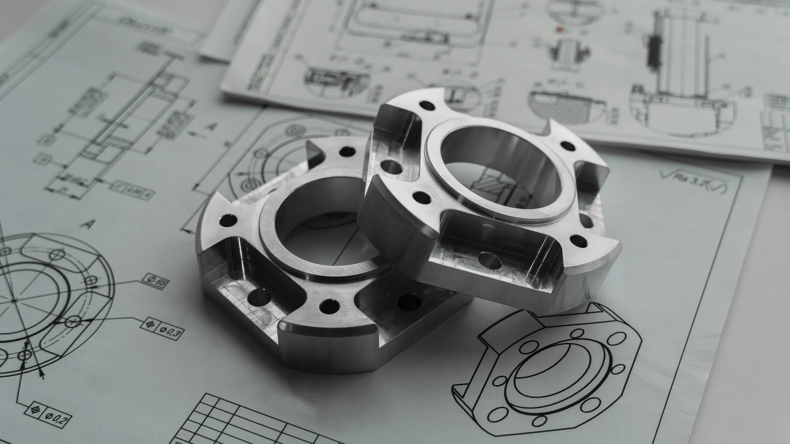 Machined parts resting on dimensioned technical drawings