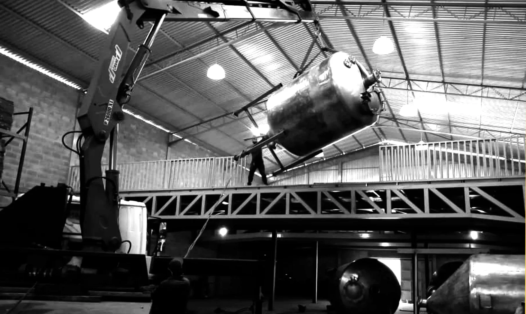 Crane lifting an industrial tank inside a steel building