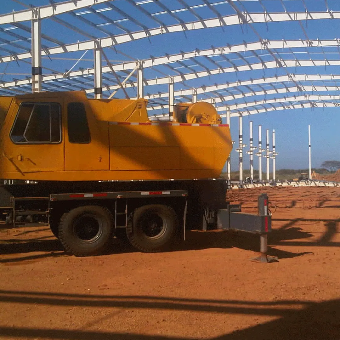 Yellow mobile crane under the steel frame of a building