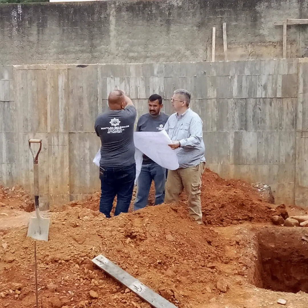Crew reviewing drawings beside a foundation excavation