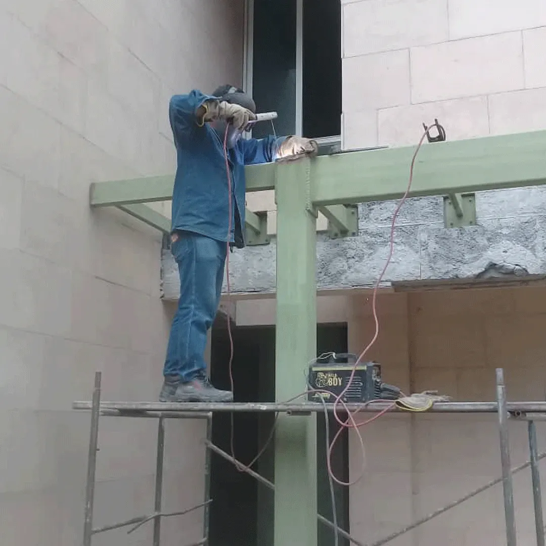 Welder on scaffolding working on a façade column