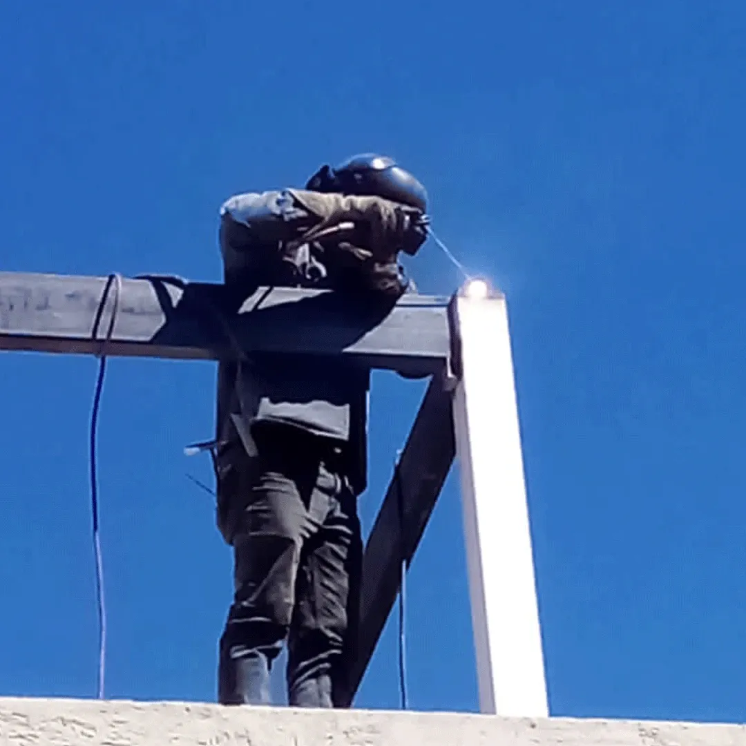 Welder working at height with the welding arc visible