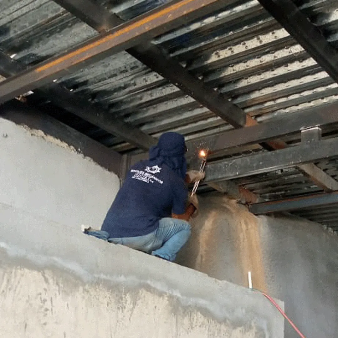 Welding an elevated structure bearing on a concrete wall