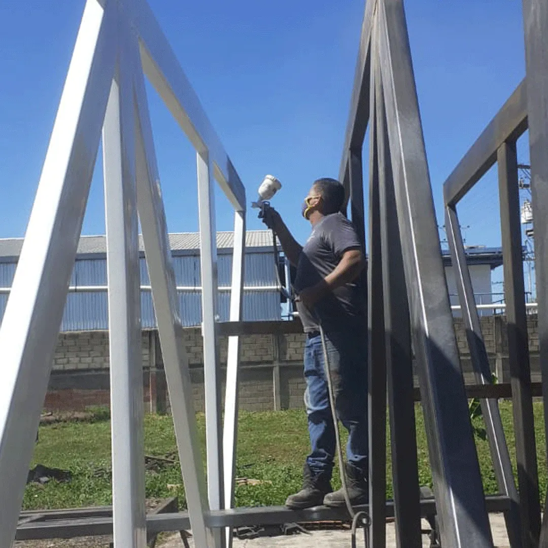 Worker spray-applying a protective coating to a steel structure